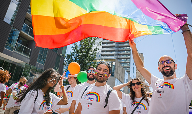 Employés de BDO participant au défilé de la Fierté et brandissant le drapeau arc-en-ciel.