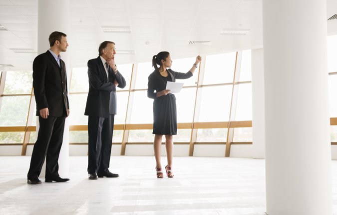 Three business professionals standing in an empty office space.