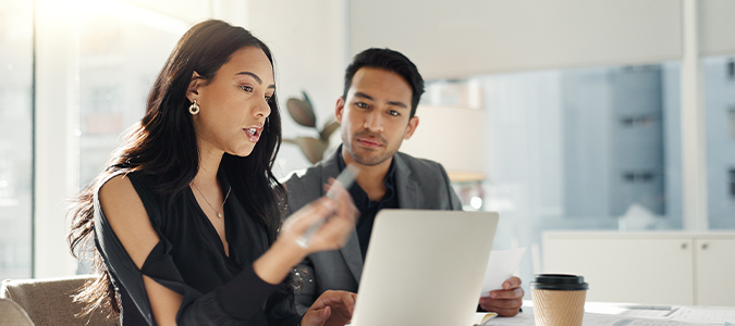 two people in discussion while working on laptop