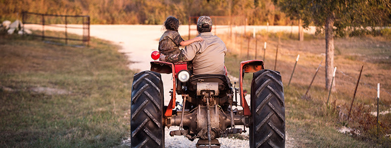 adult and young child on tractor