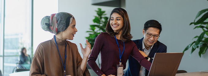 Three diverse people discussing work on a laptop computer.