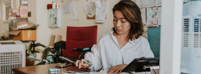 A business owner working at her desk with paper and a calculator.