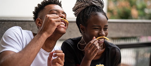 deux personnes faisant des sourires idiots avec des frites