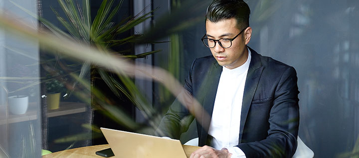 Business person sitting at table on their laptop