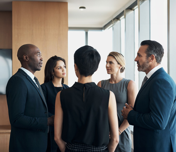 A group of business professionals having a discussion while standing in an office setting