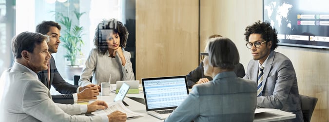 Group of colleagues sitting at a conference table in a modern office. They are in a meeting.