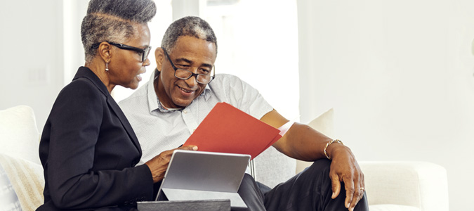 Two mature black people looking at a file and tablet