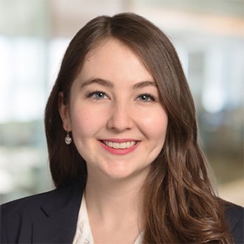 A standing female professional in a grey suit, holding a tablet.