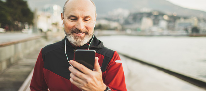 An older man taking a break from his jog and looking at his phone