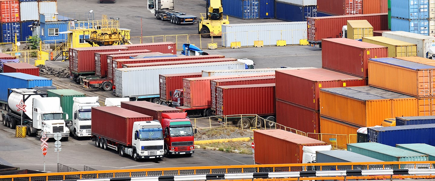 A shipping container yard with trucks.