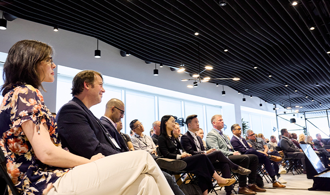 A group of people sitting in a large room watching a presentation.