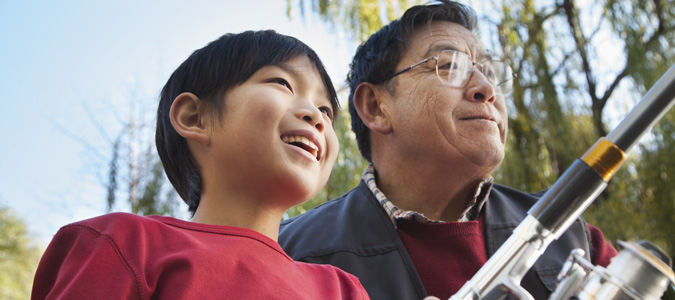 A grandfather and his grandson happily fishing