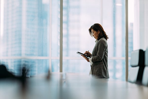 business person standing in board room looking at tablet