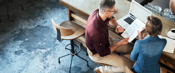 people on computer discussing paperwork