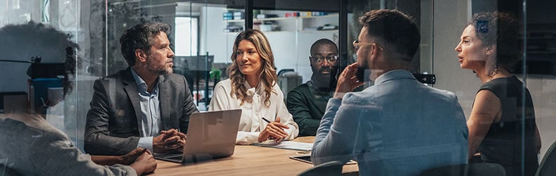 A group of business professionals at a meeting table, supporting the context of business transformation and AI.