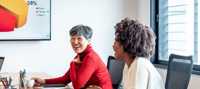 Two colleagues meeting with a chart on a big screen