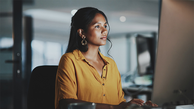 A young businesswoman working on a computer in an office at night.