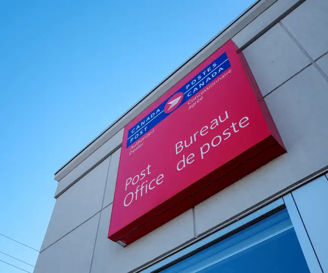 Extérieur d'un immeuble de bureaux de Postes Canada avec une affiche de Postes Canada.