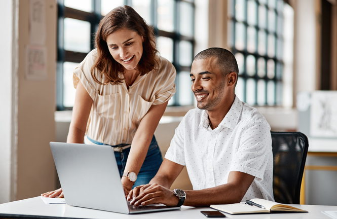 Two people look at laptop screen together.