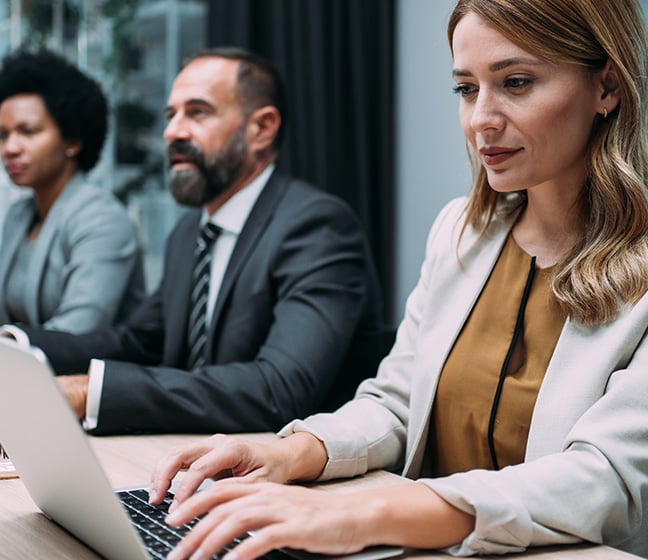 People gathered in a conference room with one person behind a laptop