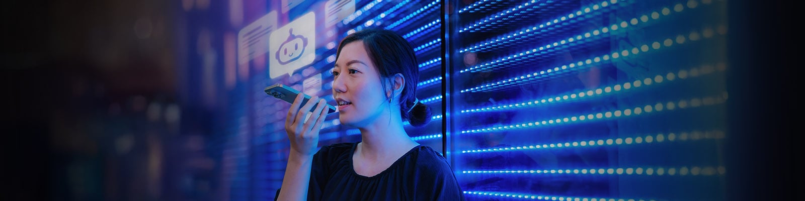 Une femme d’affaires parle à un assistant virtuel sur un téléphone intelligent devant un mur futuriste éclairé par des DEL bleues.