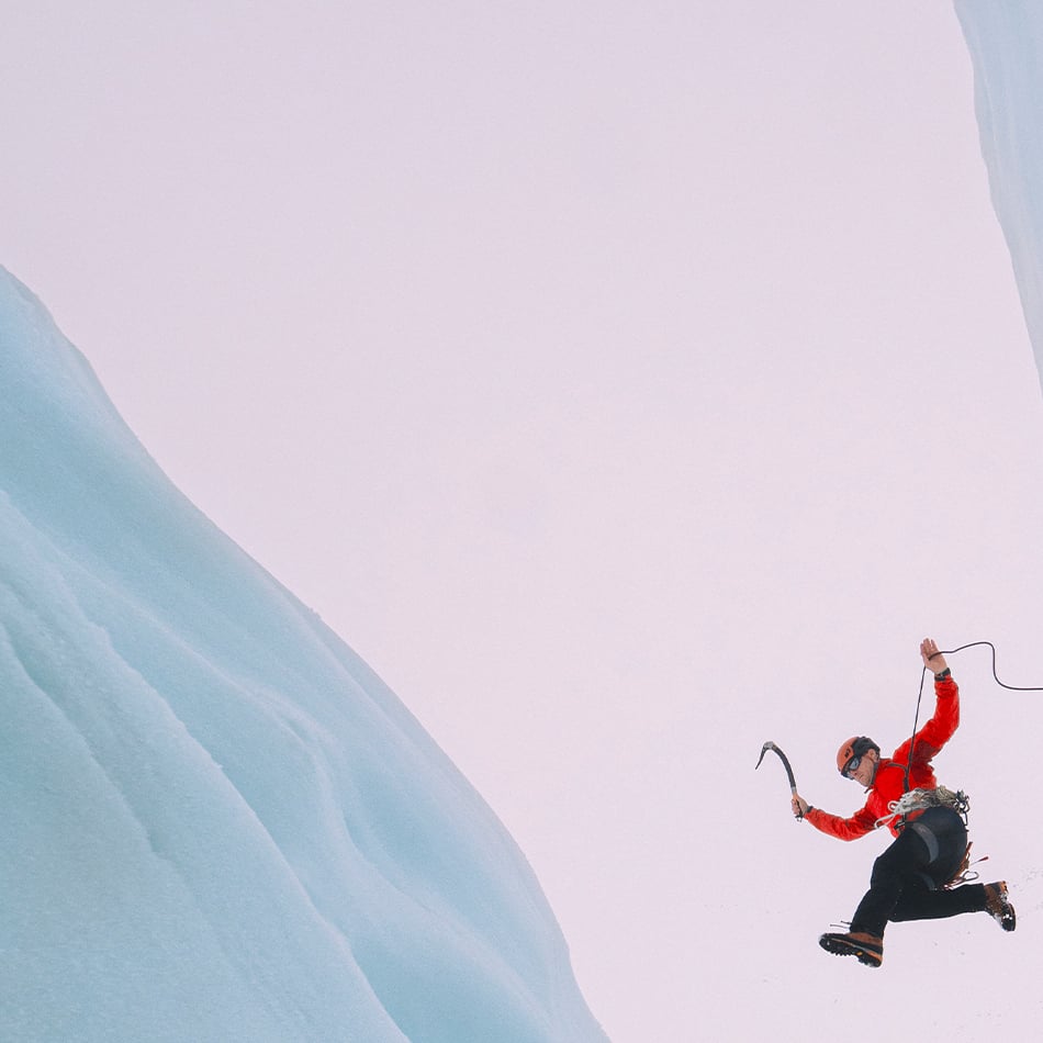 Professional mountaineer jumping across a crevasse