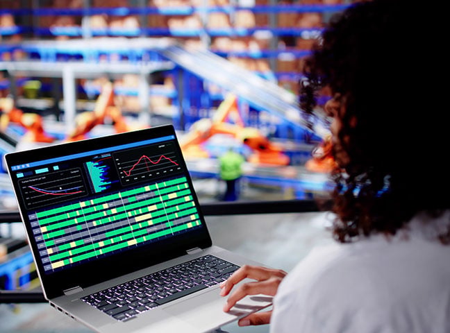 Side view of a female working on a laptop with data and charts, depicting AI in Canadian manufacturing
