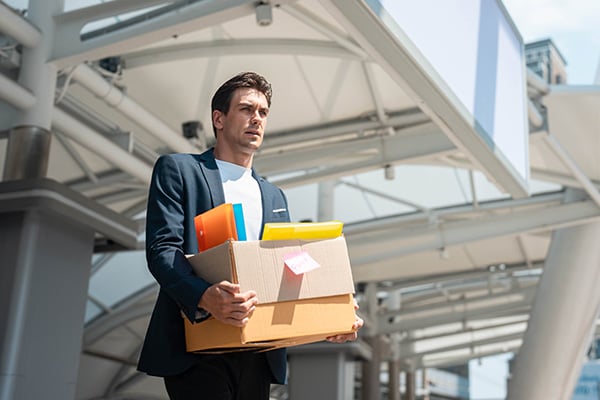 person walking out of office with personal items in box