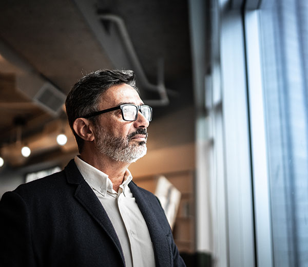 A man wearing a suit looking out of a large window.